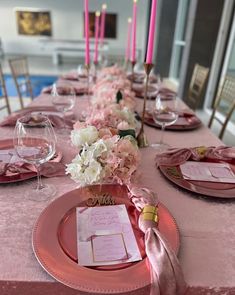 the table is set with pink plates and place settings for dinner guests to eat at