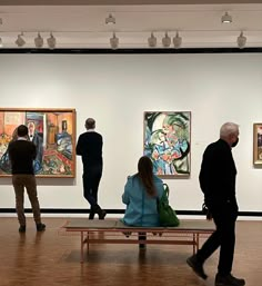 people looking at paintings on display in an art gallery