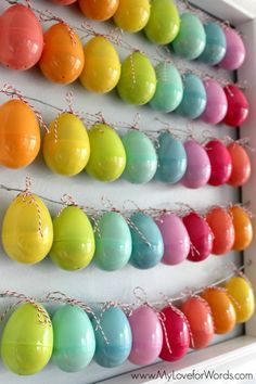 an assortment of colored eggs hanging on a wall