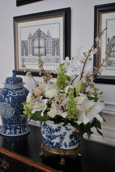 a blue and white vase sitting on top of a wooden table next to a painting