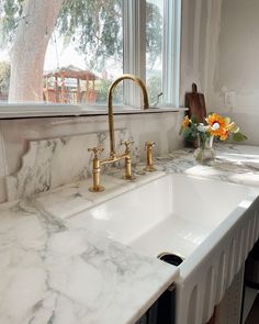 a kitchen with marble counter tops and gold faucets on the windowsills