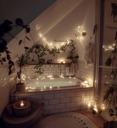 a bathroom with candles and plants in the bathtub, lights on the wall above it