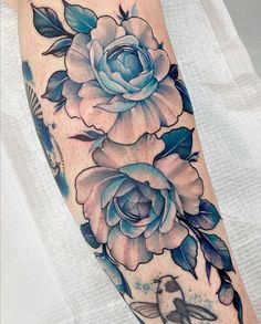 a woman's leg with roses and a bird tattoo on her left calf sleeve