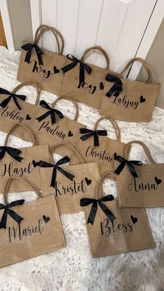 six burlap bags with black bows and names on them sitting on a bed