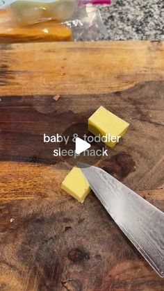 a cutting board with cheese on it and a knife next to it that says baby & todder sleep rack