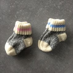 two pairs of baby socks sitting on top of a black floor next to each other