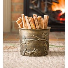 a metal cup filled with sticks sitting on top of a rug next to a fire place