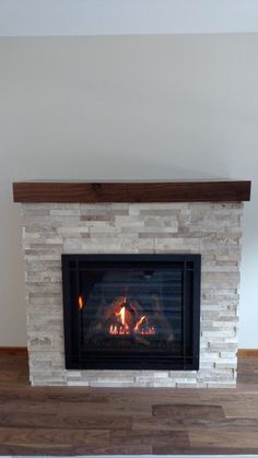 a fire place in a living room with wood flooring and a white brick fireplace