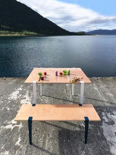 a picnic table sitting on top of a wooden bench next to a body of water