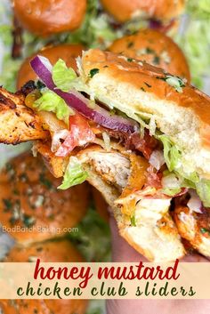 a chicken club sandwich with lettuce, tomato and onions in the foreground