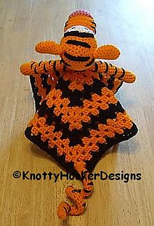 an orange and black crocheted stuffed animal sitting on top of a wooden floor