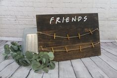 a wooden sign that says friends on it next to some plants and a potted plant