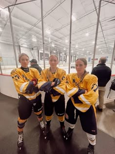 three female ice hockey players are posing for a photo in their uniforms on the ice rink