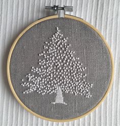 a cross stitch christmas tree with white and silver beads on it's hoop frame