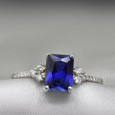 An impressive radiant cut Sapphire brings rich color to this ring, contrasted by brilliant diamond side stones set in a shimmering 10,14 or 18 Karat gold setting.- Made to Order, Perfectly finished, Fast shipping fully insured and trackable online.- Gemstone info: Sapphire corundum 8x6 mm, Excellent cut, 1.54 ct- Diamond info: 16 x Diamonds ranging from 1-1.75mm, VS-E, 0.15 ctw- Arrives gift ready with a certificate of authenticity Timeless Emerald Cut Sapphire Promise Ring, Timeless Emerald-cut Sapphire Promise Ring, Fine Jewelry Square Cut Diamond Promise Ring, Sapphire Rings With Prong Setting And Radiant Cut, Timeless Sapphire Diamond Ring With Emerald Cut, Square Cut Diamond Promise Ring, White Gold Sapphire Ring With Square Cut Diamond, Emerald Cut Sapphire Promise Ring With Center Stone, Square Cut Sapphire Ring In White Gold With Diamonds