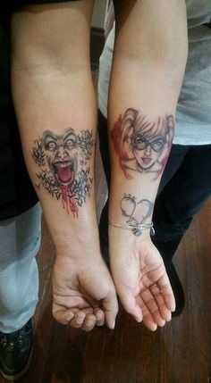 two people are holding hands with tattoos on their arms and both have faces painted on them