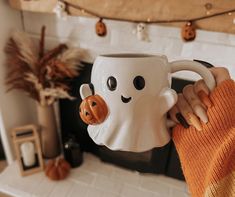 a person holding a coffee mug with a ghost face on it