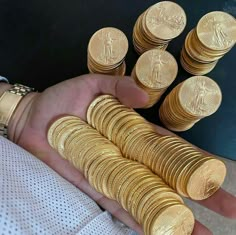 a person is holding some gold coins in their hand and it looks like they are counting them