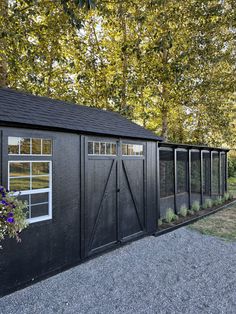 a large black shed with windows and plants in the window boxes on the side of it