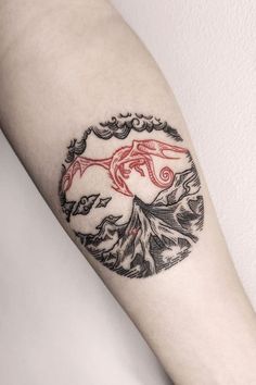 a tattoo on the arm of a person with a red and black bird in it