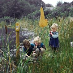 three children are playing in the water near a yellow object that looks like a flower