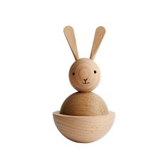 a wooden toy rabbit sitting on top of a bowl with its head in the middle