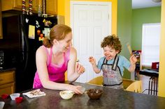 a woman and child in the kitchen with food on the counter, smiling at each other