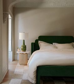 a bedroom with a green headboard and white bedding