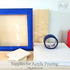 a wooden frame sitting on top of a table next to a pair of blue tape