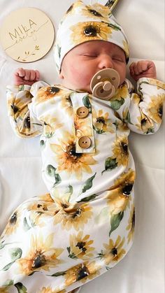 a newborn baby wearing a sunflower outfit and pacifier