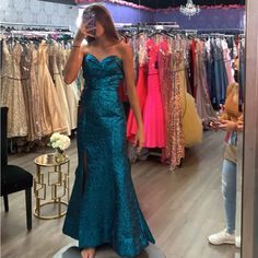 a woman taking a selfie in front of a mirror wearing a blue evening gown