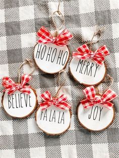 four christmas ornaments with the words believe, merry, and joy hanging from them on a checkered tablecloth