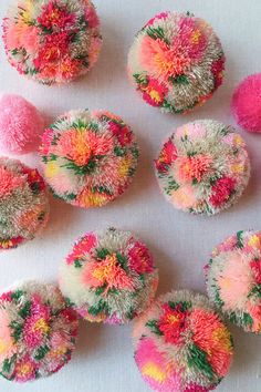 there are many different types of pom poms on the white tablecloth with pink, yellow and green colors