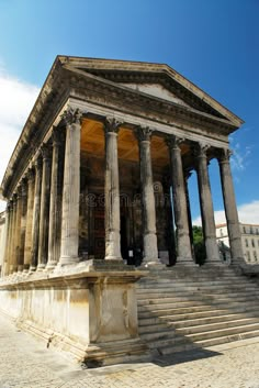 an old building with columns and pillars on the outside, against a blue sky background