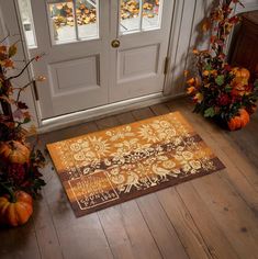 an orange and brown rug on the floor in front of a door with pumpkins