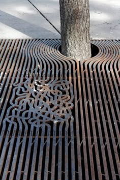 a metal grate on the ground with a tree in the middle and an intricate design