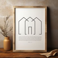 an art print with three houses on it next to a potted plant and a vase