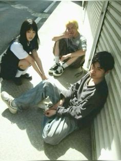 four young people sitting on the side of a building