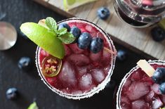 two glasses filled with blueberries and limes