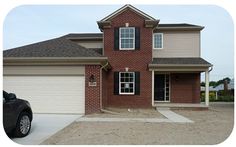 a car is parked in front of a brick house with two garage doors and windows