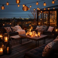 an outdoor deck with candles and pillows on it, lit up by lights strung from the ceiling