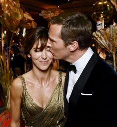 a man in a tuxedo kisses a woman's cheek at an event