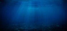 an underwater view of the ocean with sunlight shining on the water's surface and deep blue water