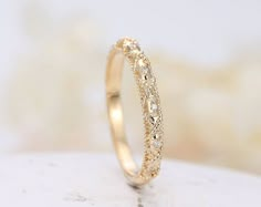 a gold wedding band with small diamonds on the inside and outside, sitting on top of a white surface