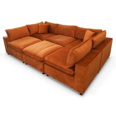 an orange sectional sofa with pillows on the bottom and back ends, in front of a white background