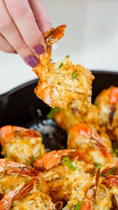 a person is dipping some food into a skillet with shrimp and scallops