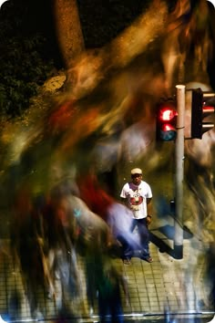 a blurry photo of a man standing on the side of a road next to a traffic light