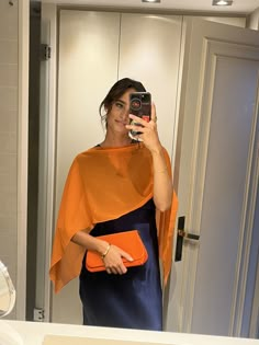 a woman taking a selfie in front of a mirror wearing an orange and blue dress