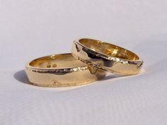 two gold wedding rings sitting on top of each other