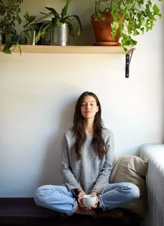 a woman is sitting on the floor with her eyes closed while holding a coffee cup